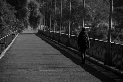Rear view of man walking on footbridge