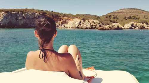 Rear view of woman in sea against clear sky