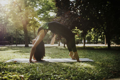Yoga instructor practicing bridge pose in park