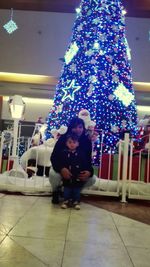 Full length of friends in illuminated christmas lights