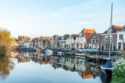 Buildings by river against sky in city