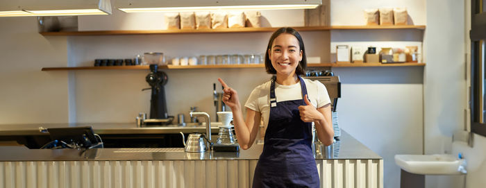 Portrait of young woman standing in kitchen