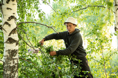 Side view of young man standing against plants