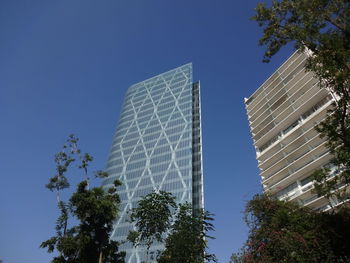 Low angle view of modern buildings against clear blue sky