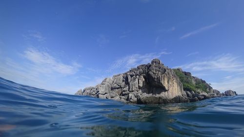 Rock formation in sea against blue sky