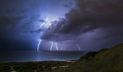 Scenic view of lightning over sea against dramatic sky