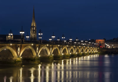 Arch bridge over river in city at night