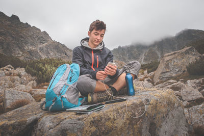 Low angle view of man sitting on rock