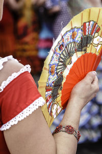 Midsection of woman wearing multi colored umbrella