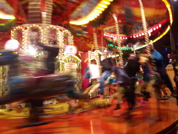 Illuminated carousel in amusement park at night