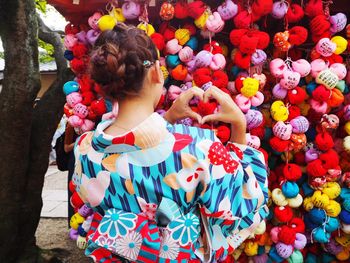 Woman making heart shape by multi colored toys in market