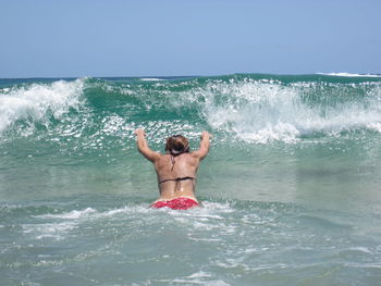 Full length of shirtless man in swimming pool against sea