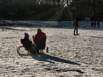 Rear view of people riding motorcycle on street during winter