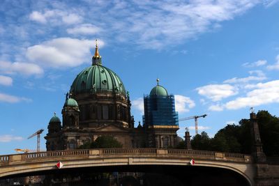 Bridge by cathedral against sky