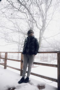 Man standing at a balcony while snowing 