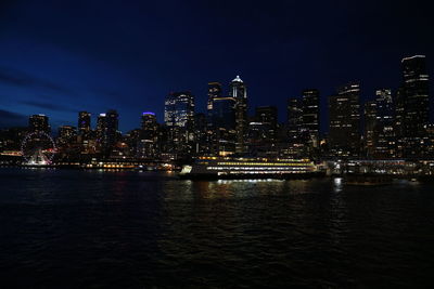 Seattle downtown from water against sky at night