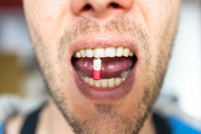 Close-up of man eating a pill 