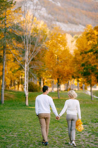 Rear view of couple walking on field during autumn
