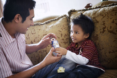 Father and son sitting on sofa at home