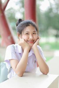 Portrait of smiling young woman sitting at table