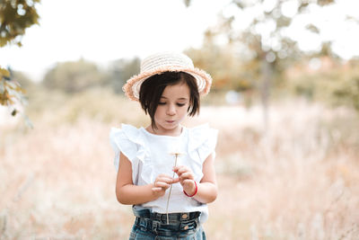 Baby girl 3-4 year old holding flower standing in meadow closeup. childhood.