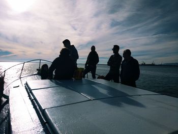 Rear view of people standing by sea against sky