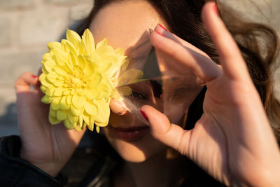 Close-up of woman holding yellow flower and crystal