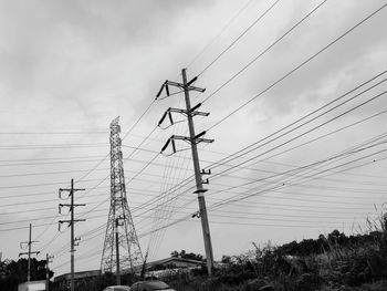 Low angle view of electricity pylon on field against sky