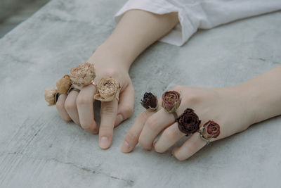 Cropped hands of young woman wearing rose shape rings on retaining wall