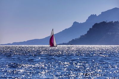 Sailboat on sea against clear blue sky