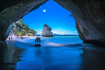 Friends standing on rock in arch cave at beach