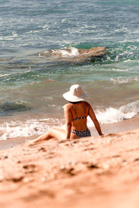 Rear view of woman sitting at beach