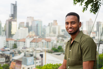 Portrait of young man standing against buildings