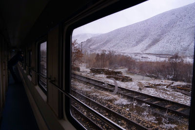 Railroad tracks seen through train window during winter