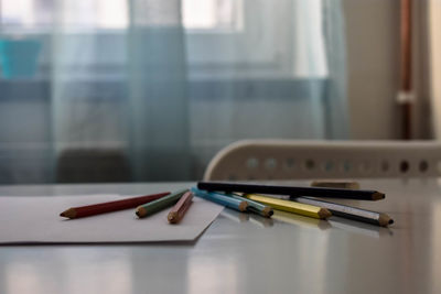 Close-up of colored pencils with papers on table