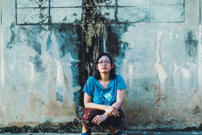 Portrait of woman sitting against wall