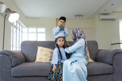 Full length of couple sitting on sofa at home