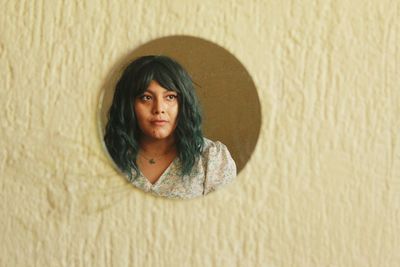 Portrait of young woman standing against wall