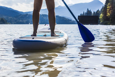 Low section of woman paddleboarding in lake