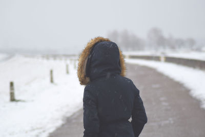 Woman standing on road during snowfall