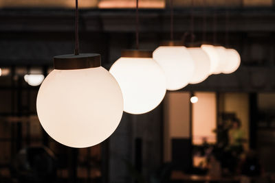 Low angle view of illuminated light bulb hanging from ceiling