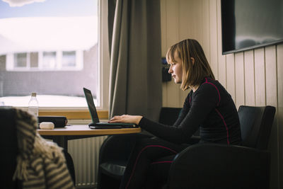 Teenage girl using laptop while doing homework in living room