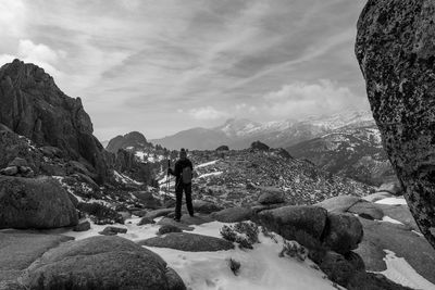 Rear view of man standing on rocks against sky