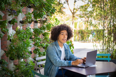 Portrait of young woman using laptop at park