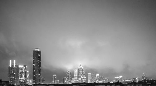 Illuminated buildings in city against sky at night