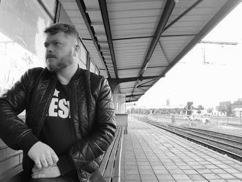 Man looking away while sitting at railroad station