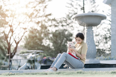 Full length of woman with dog sitting at park