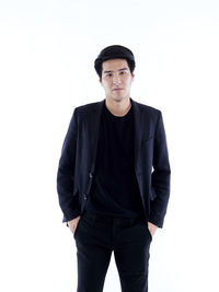Portrait of young man standing against white background