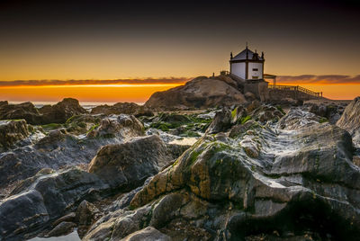 Lighthouse amidst buildings against sky during sunset