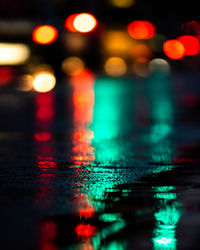 Reflection of illuminated lights on wet table in city at night